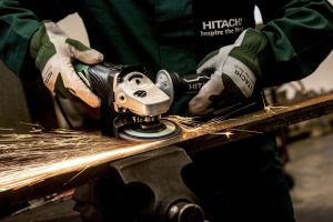 a man using a metal abrasive to grind metal on a workbench